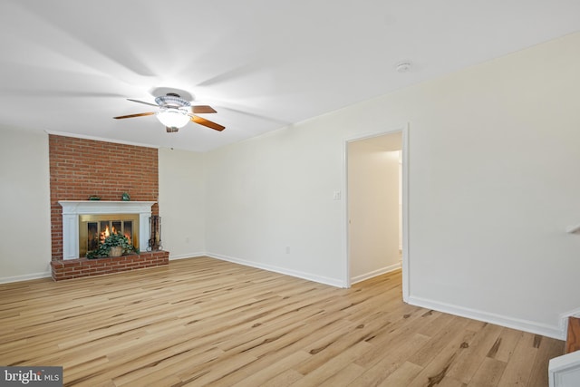 unfurnished living room with a ceiling fan, a brick fireplace, light wood-style flooring, and baseboards