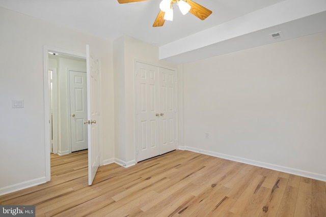 unfurnished bedroom with baseboards, visible vents, ceiling fan, light wood-type flooring, and a closet