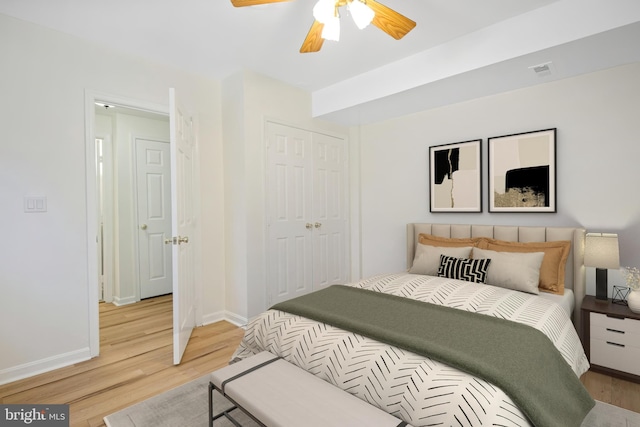 bedroom with ceiling fan, visible vents, baseboards, light wood-style floors, and a closet