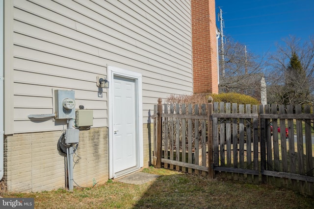 property entrance with a chimney and fence