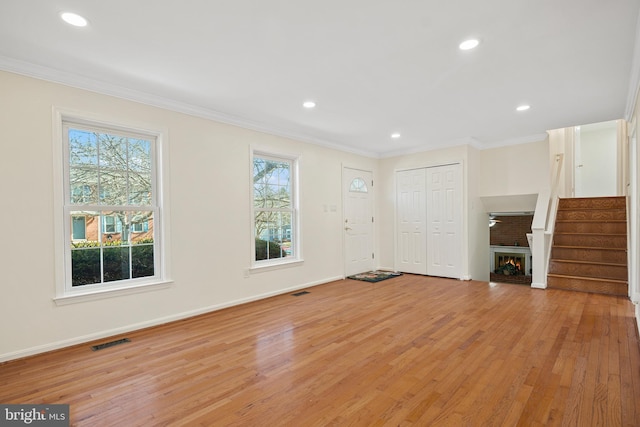 unfurnished living room featuring stairway, plenty of natural light, visible vents, and crown molding