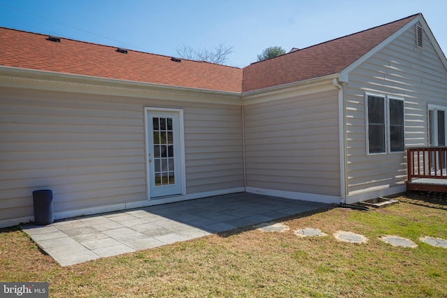 view of side of home with a shingled roof, a patio area, and a yard