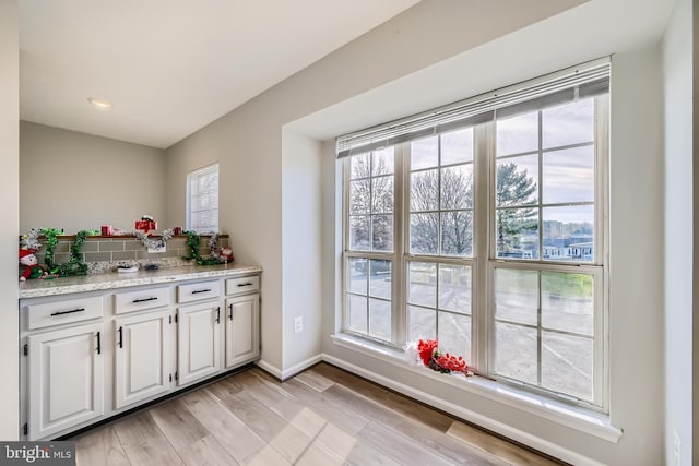 kitchen featuring white cabinetry, light hardwood / wood-style floors, and light stone counters