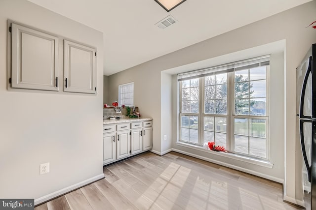 kitchen featuring fridge, light stone countertops, and light hardwood / wood-style flooring