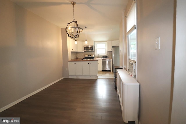 kitchen with dark wood-type flooring, white cabinetry, tasteful backsplash, hanging light fixtures, and appliances with stainless steel finishes