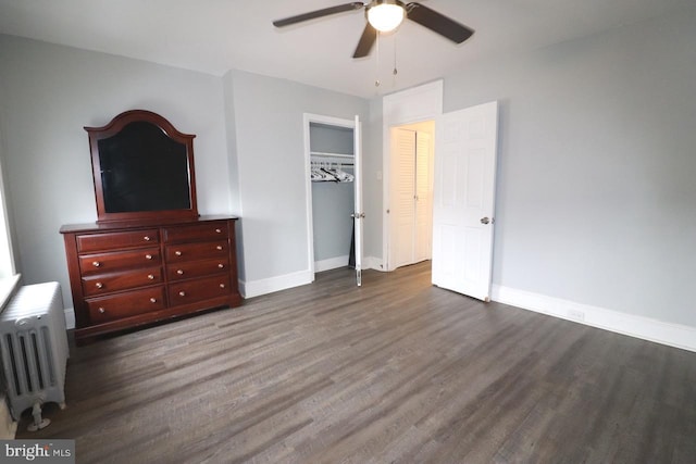 unfurnished bedroom with ceiling fan, radiator heating unit, dark hardwood / wood-style flooring, and a closet