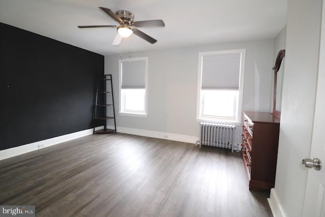 unfurnished bedroom with ceiling fan, dark hardwood / wood-style floors, and radiator