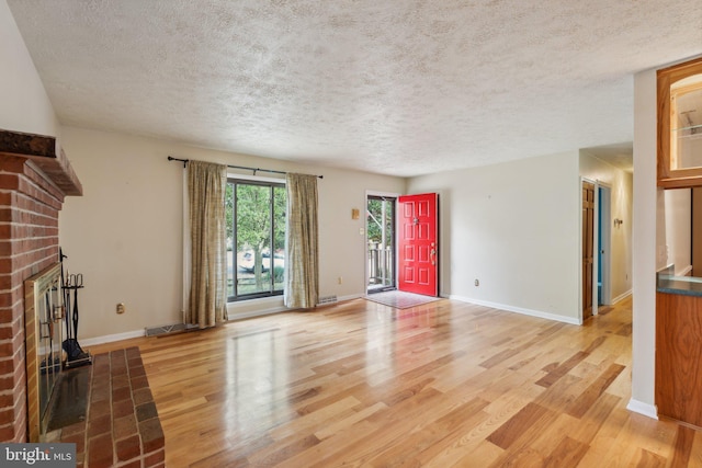 unfurnished living room featuring hardwood / wood-style flooring, a brick fireplace, and a textured ceiling