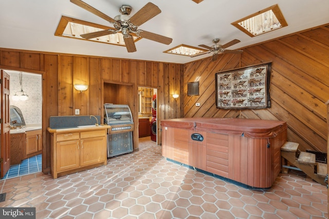 interior space featuring ceiling fan, wooden walls, a skylight, and hanging light fixtures