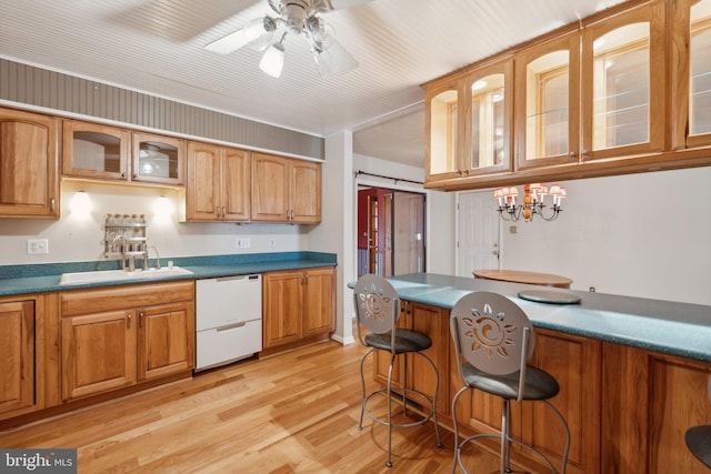 kitchen featuring sink, a breakfast bar, ceiling fan, white dishwasher, and light wood-type flooring