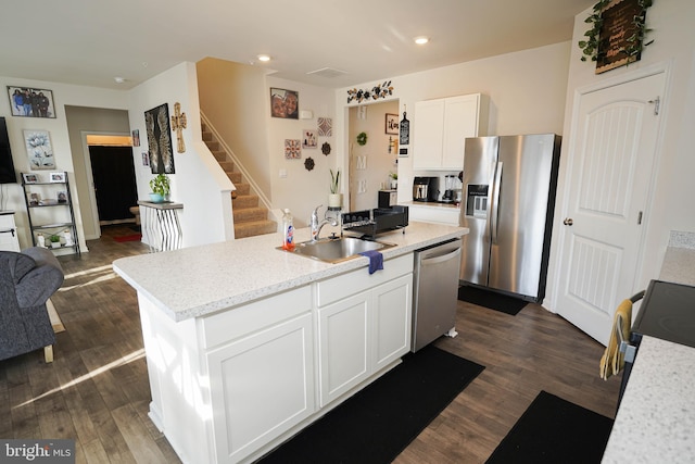 kitchen with sink, white cabinetry, stainless steel appliances, dark hardwood / wood-style floors, and an island with sink