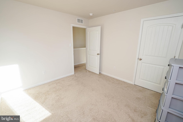 unfurnished bedroom with light carpet and washer / clothes dryer