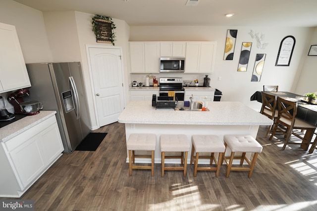 kitchen with white cabinetry, appliances with stainless steel finishes, a breakfast bar, and an island with sink