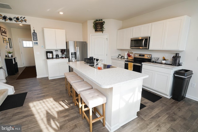 kitchen featuring a breakfast bar, sink, an island with sink, stainless steel appliances, and white cabinets