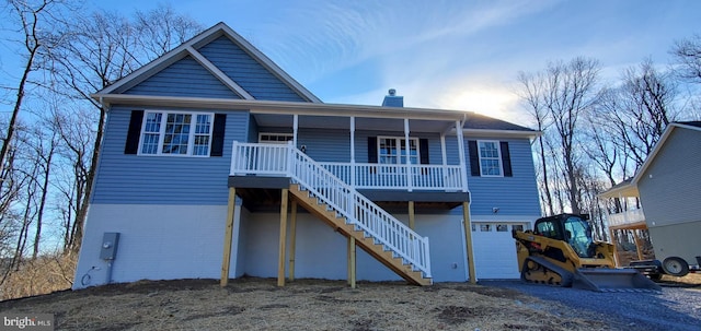 rear view of property featuring covered porch, a chimney, stairs, and a garage