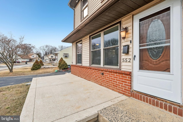 doorway to property featuring brick siding and a residential view