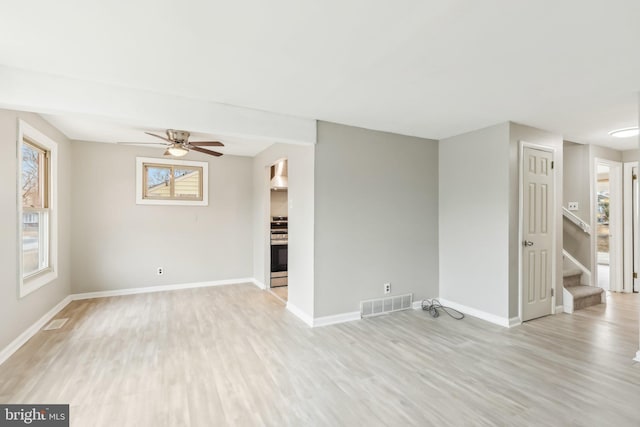 empty room with light wood finished floors, stairs, and visible vents