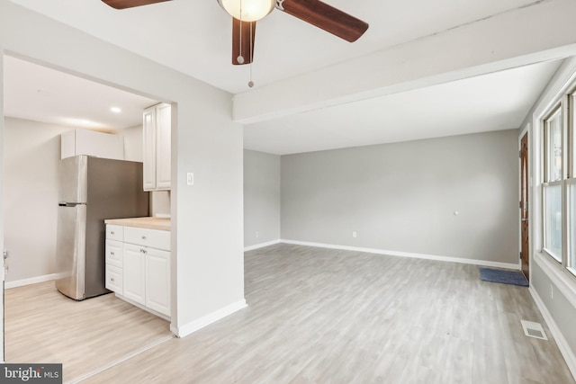 kitchen featuring light wood-type flooring, freestanding refrigerator, visible vents, and white cabinetry