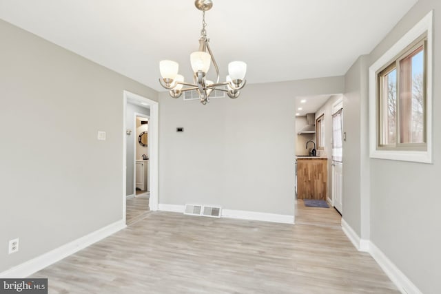 unfurnished dining area featuring visible vents, a sink, light wood finished floors, and baseboards