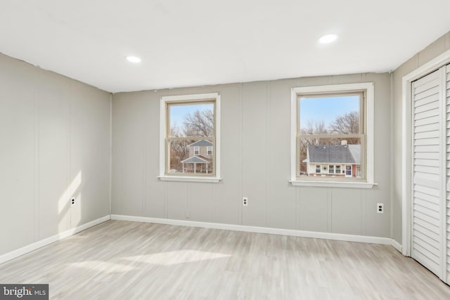 interior space featuring recessed lighting, a decorative wall, baseboards, and wood finished floors