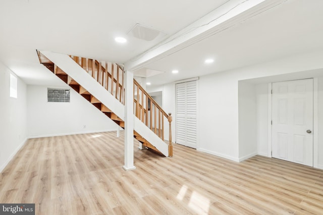 finished below grade area with recessed lighting, wood finished floors, visible vents, baseboards, and stairway