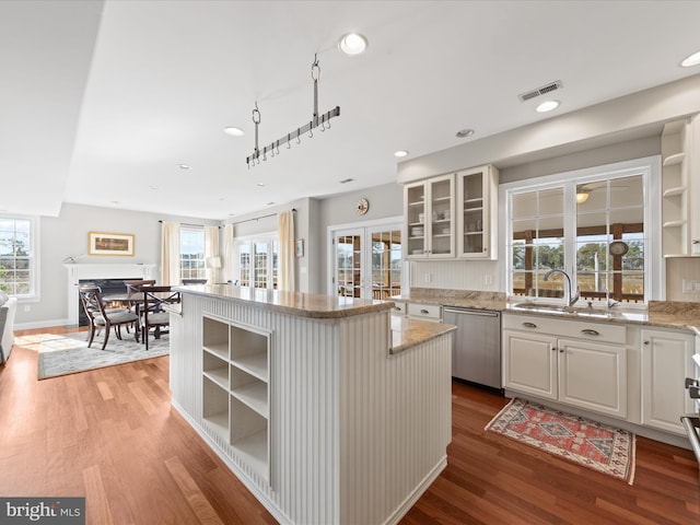 kitchen featuring a sink, visible vents, white cabinets, dishwasher, and glass insert cabinets