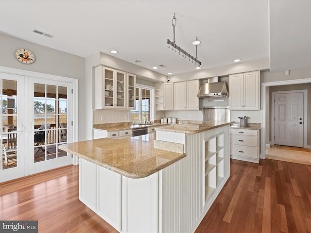 kitchen with a kitchen island, visible vents, white cabinets, open shelves, and glass insert cabinets