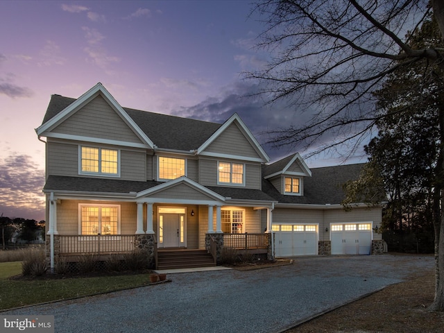 view of front of home featuring roof with shingles, a porch, an attached garage, stone siding, and driveway