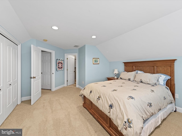 bedroom with baseboards, vaulted ceiling, a closet, and light colored carpet