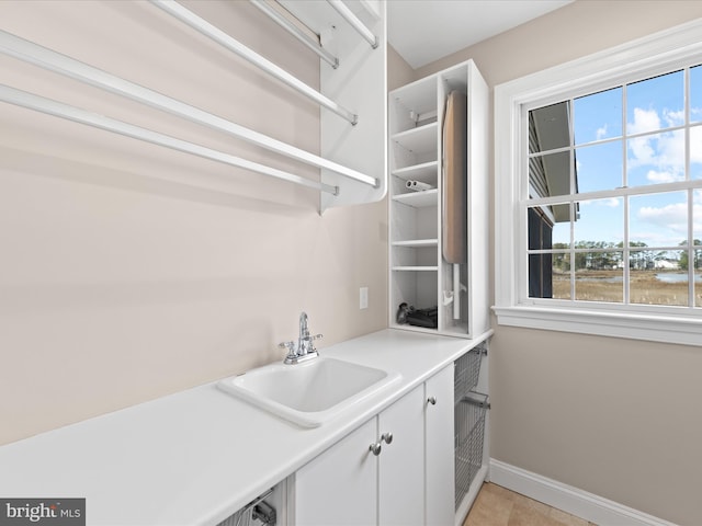 washroom with cabinet space, a sink, and baseboards