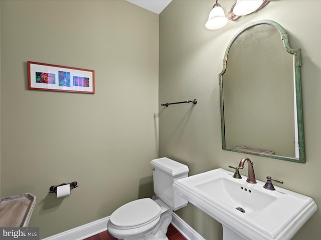 half bath with a sink, toilet, and baseboards