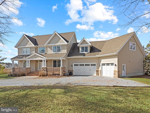 view of front of property with a garage, stone siding, gravel driveway, covered porch, and a front yard