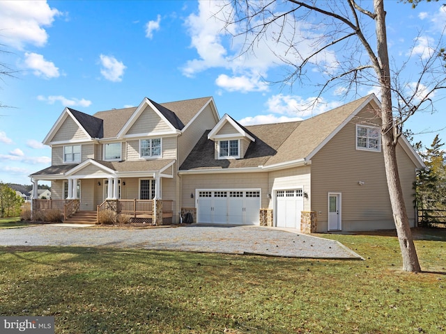 view of front of house with an attached garage, covered porch, stone siding, driveway, and a front yard