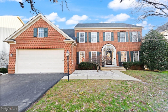 view of front of house with aphalt driveway, an attached garage, a front yard, and brick siding