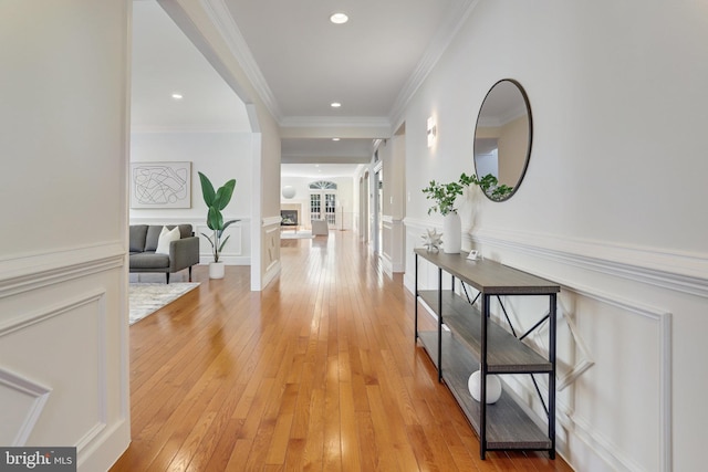 hallway with crown molding and light hardwood / wood-style flooring