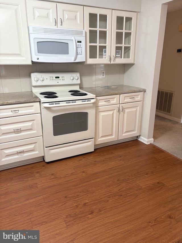 kitchen featuring tasteful backsplash, white cabinetry, dark wood-type flooring, and white appliances