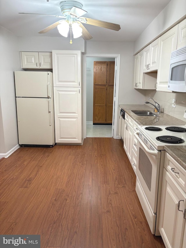 kitchen with white appliances, wood-type flooring, and white cabinets