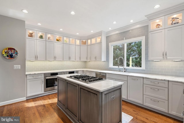 kitchen featuring appliances with stainless steel finishes, a sink, glass insert cabinets, and light stone countertops