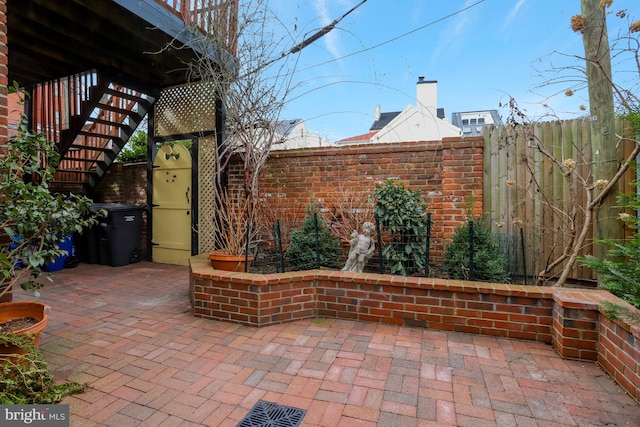 view of patio featuring fence and stairway