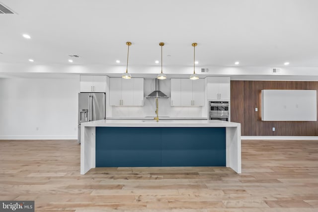 kitchen featuring hanging light fixtures, wall chimney exhaust hood, light countertops, and white cabinets