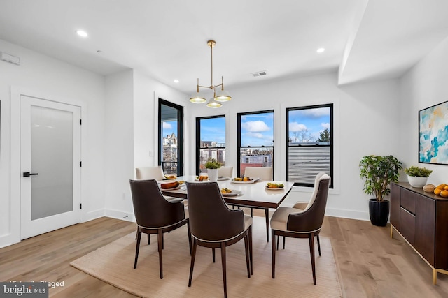 dining area featuring baseboards, light wood finished floors, recessed lighting, and an inviting chandelier