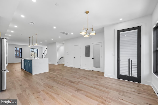 kitchen featuring pendant lighting, recessed lighting, light countertops, an island with sink, and light wood-type flooring