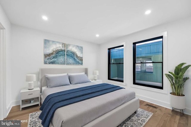 bedroom with recessed lighting, visible vents, baseboards, and wood finished floors