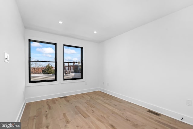 empty room with light wood finished floors, baseboards, and visible vents