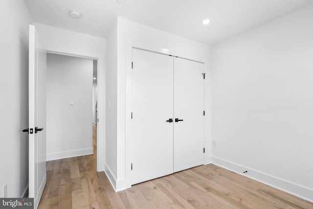 unfurnished bedroom with a closet, light wood-style flooring, and baseboards