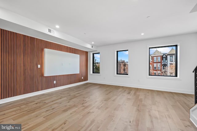 spare room with recessed lighting, visible vents, light wood-style floors, wooden walls, and baseboards