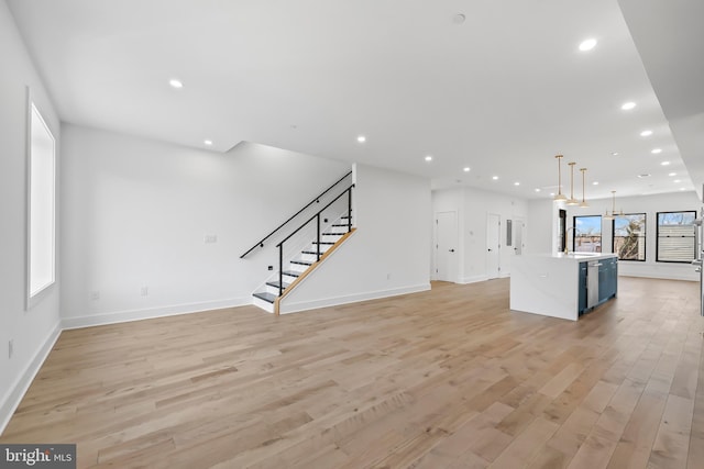 unfurnished living room with light wood-style floors, baseboards, stairway, and recessed lighting