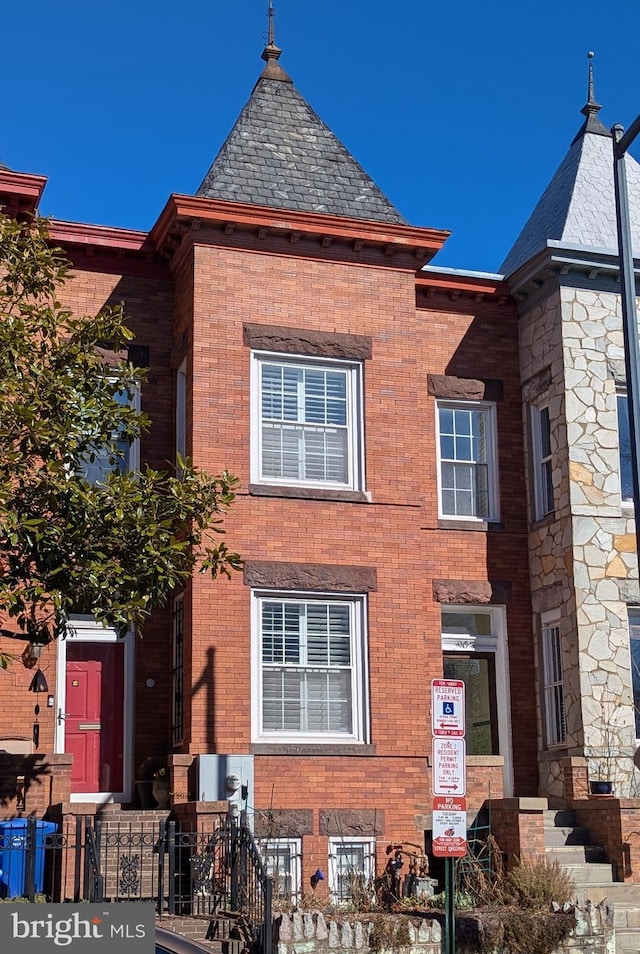 view of front of home with brick siding and a high end roof