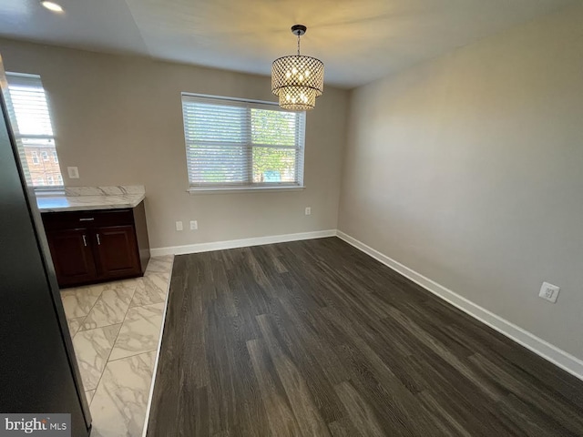 unfurnished dining area featuring an inviting chandelier and plenty of natural light