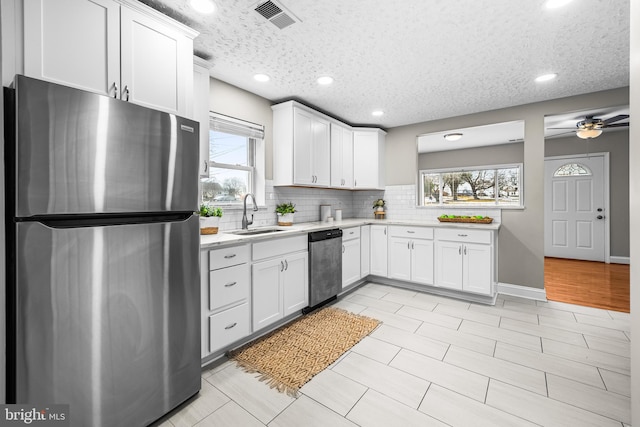 kitchen featuring sink, decorative backsplash, stainless steel appliances, and white cabinets